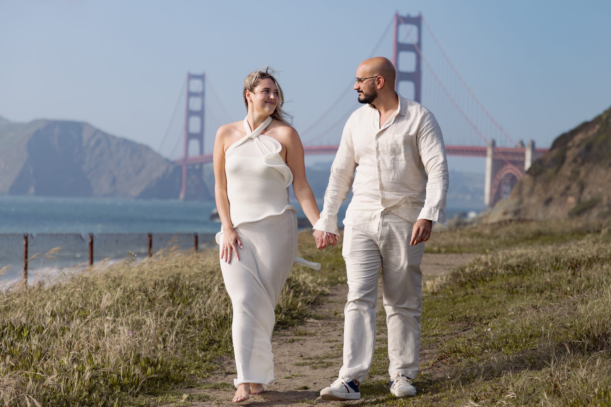 Couple walking at Baker Beach with Golden Gate Bridge