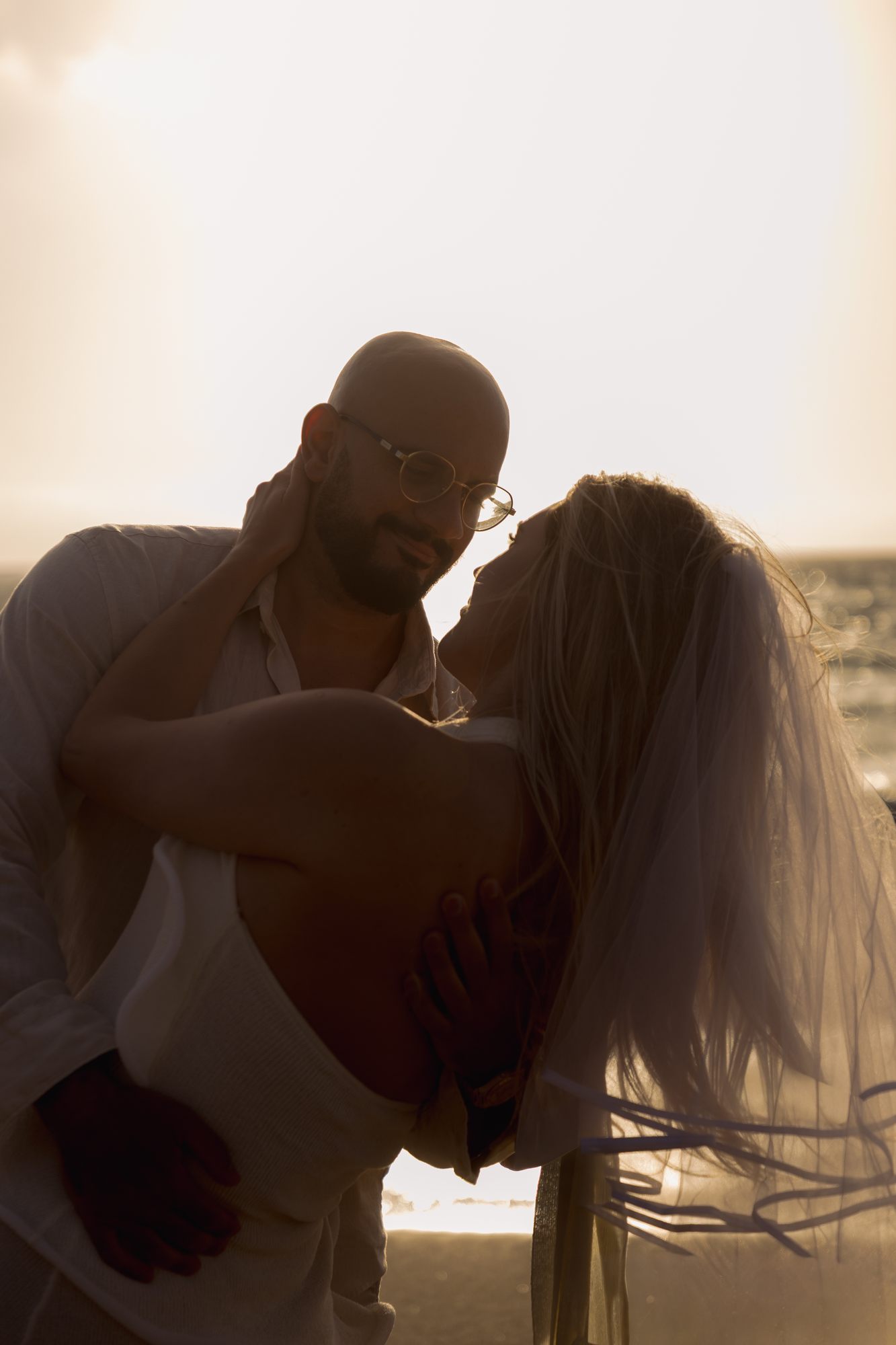 Couple silhouetted in backlit sunset embrace