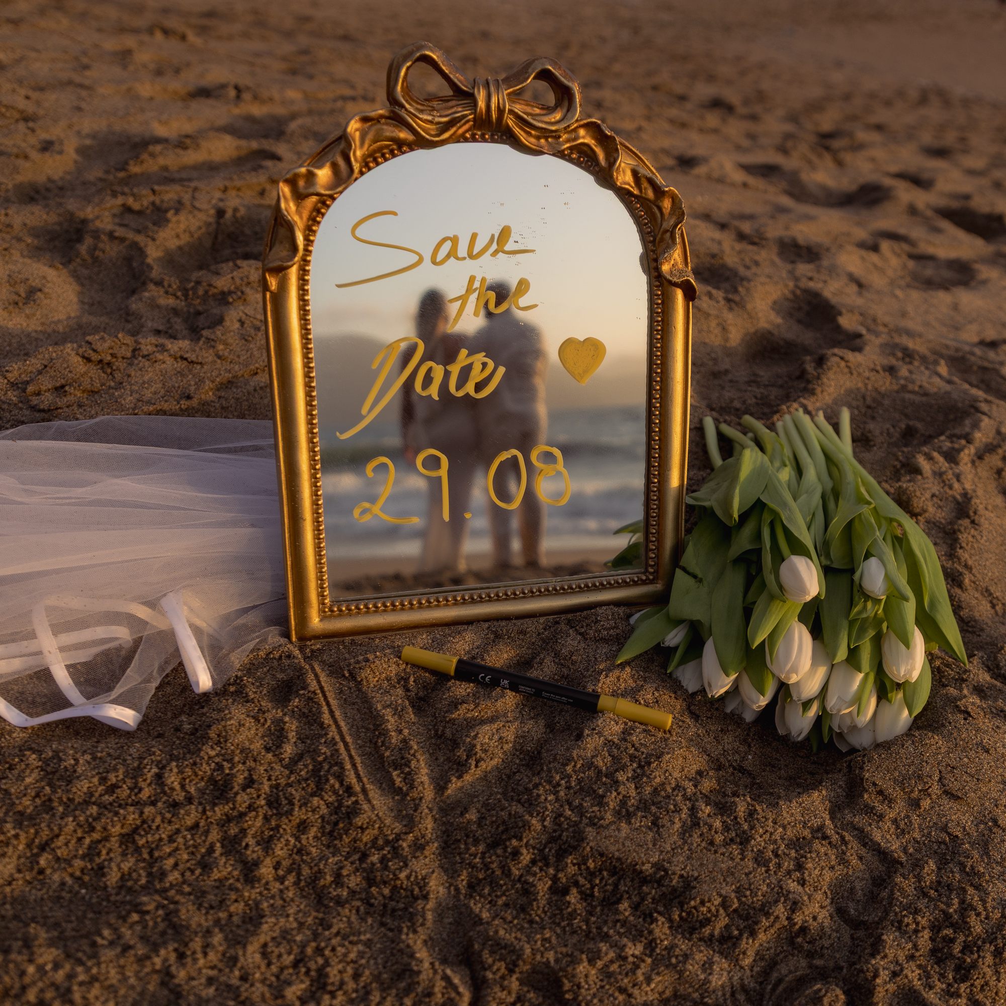 Save the date mirror on sand with tulips and veil