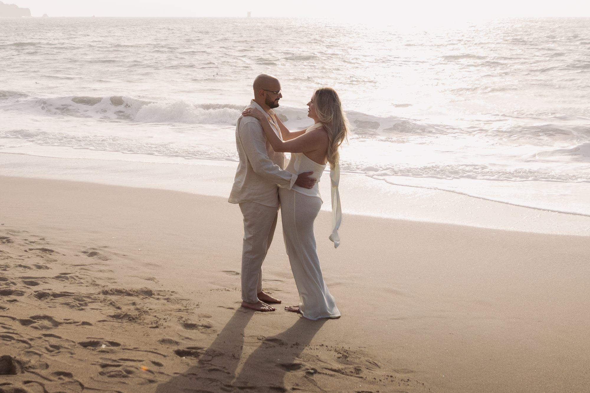 Couple dancing at the shoreline, golden haze