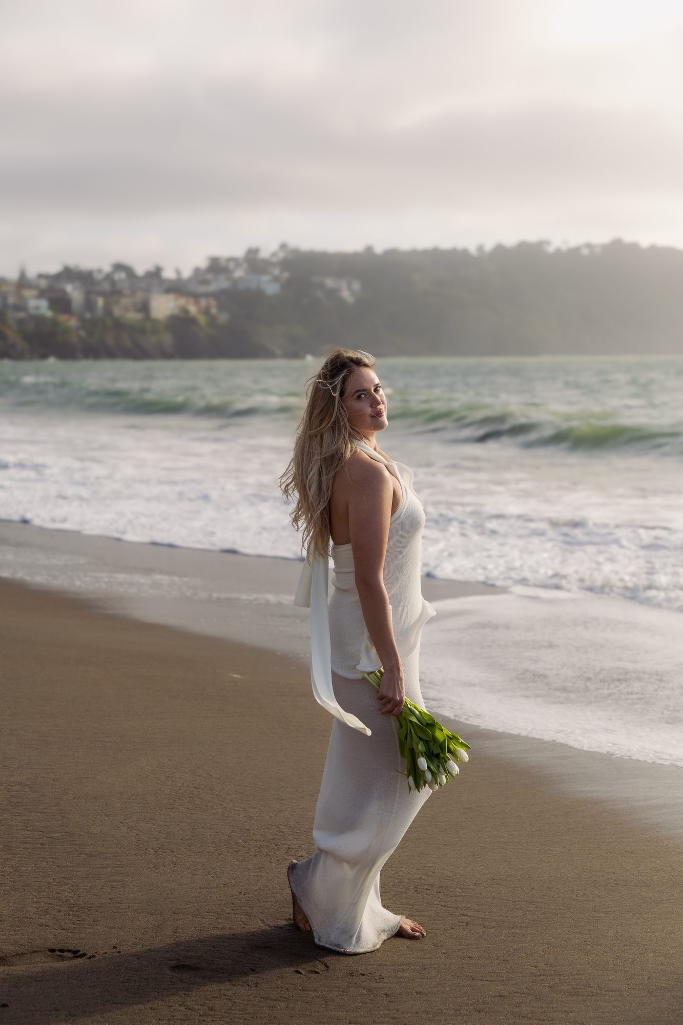 Woman looking back over shoulder with bouquet, waves behind her