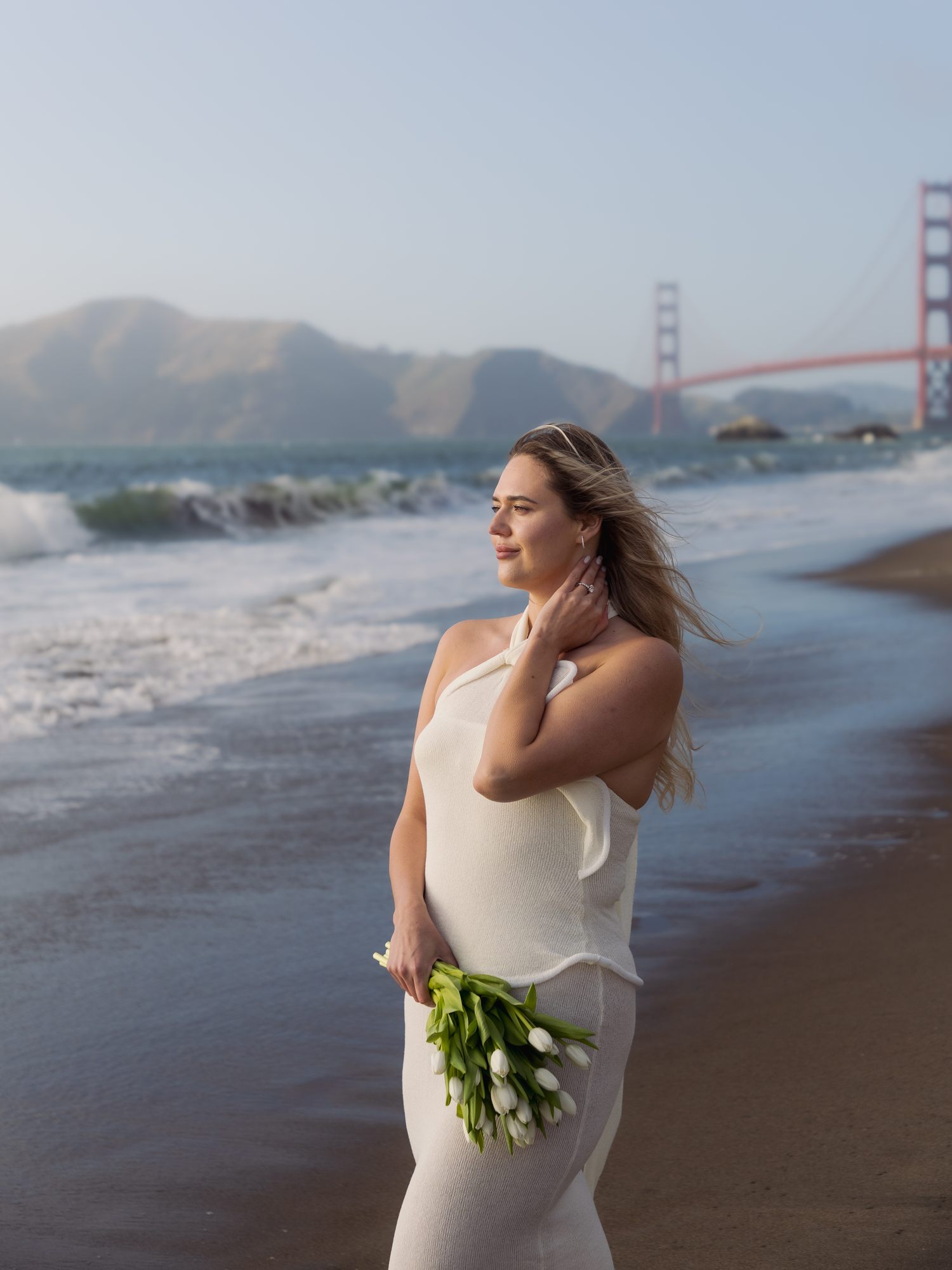 Woman with bouquet at Baker Beach, Golden Gate behind her