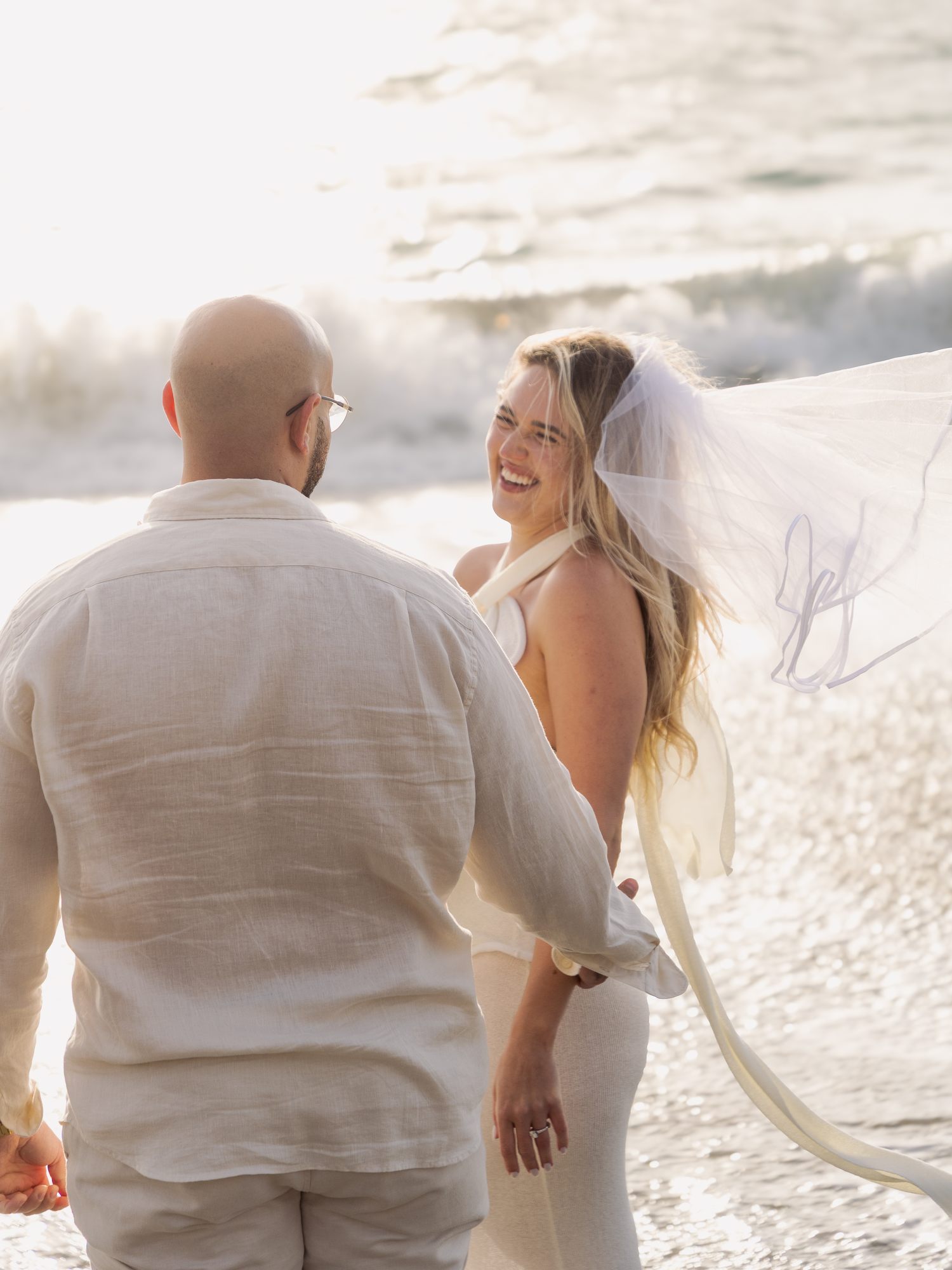 Bride laughing with veil flying, Baker Beach